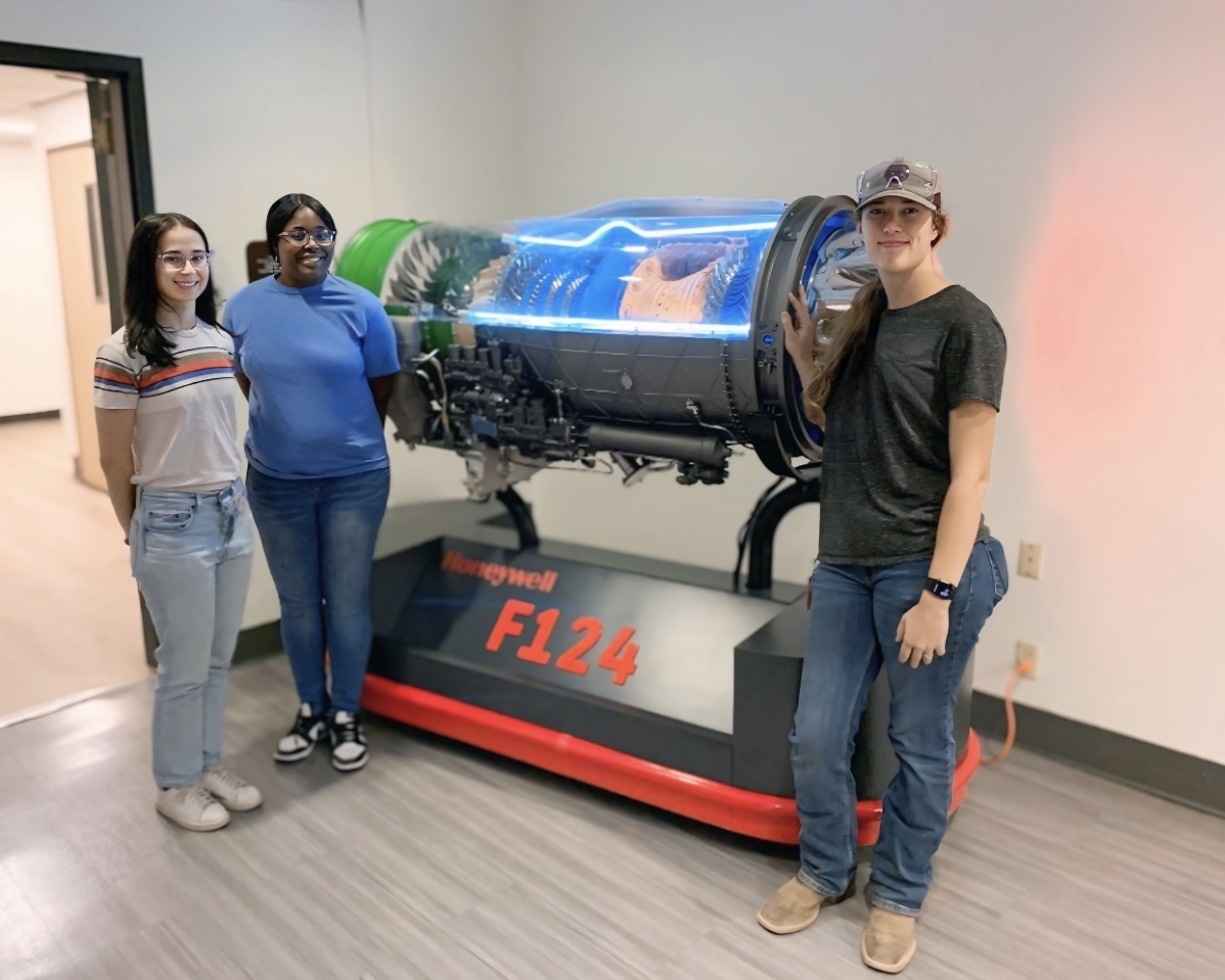 Students posing in front of Honeywell F124 technology.