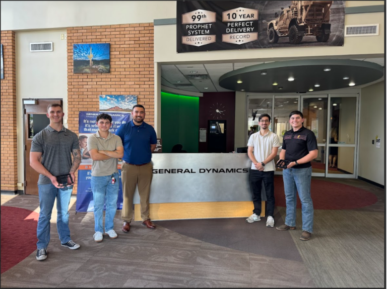 Group photo for team project taken in front of General Dynamics desk